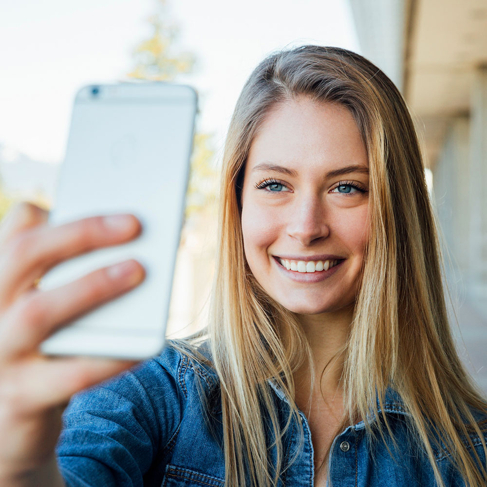 A lady holding her phone infront of her face